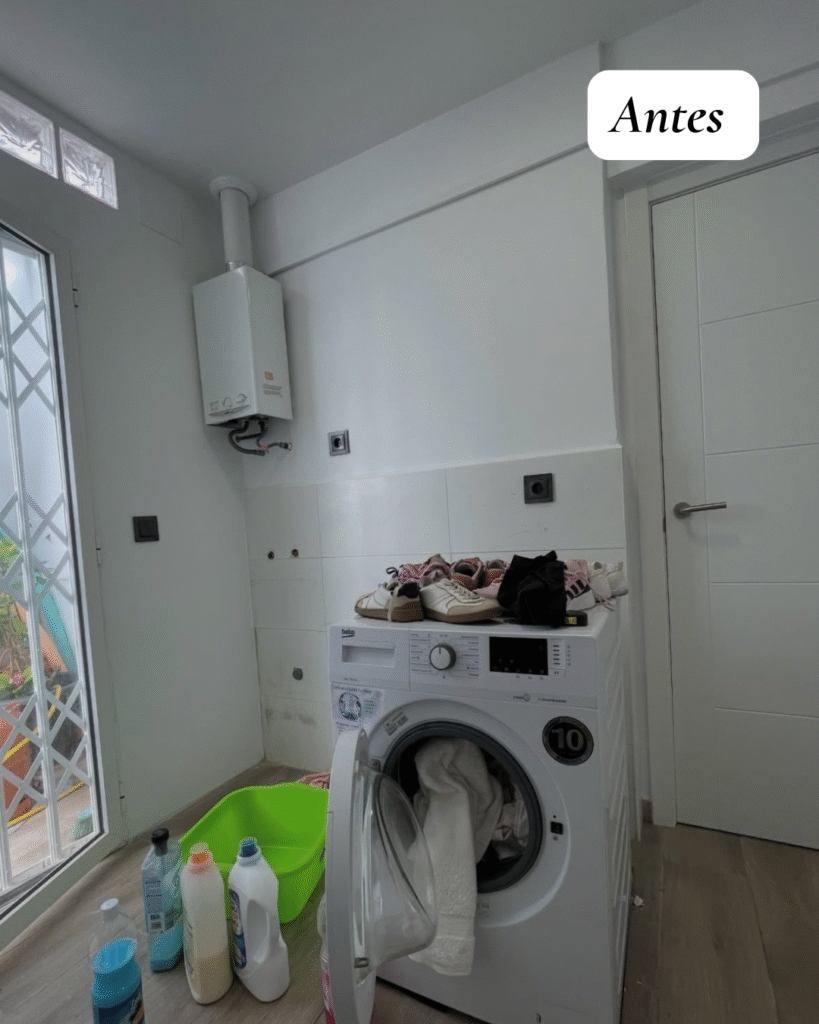 Lavandería pequeña reformada en Castellón con lavadora integrada, muebles blancos, encimera de madera y baldas decorativas.