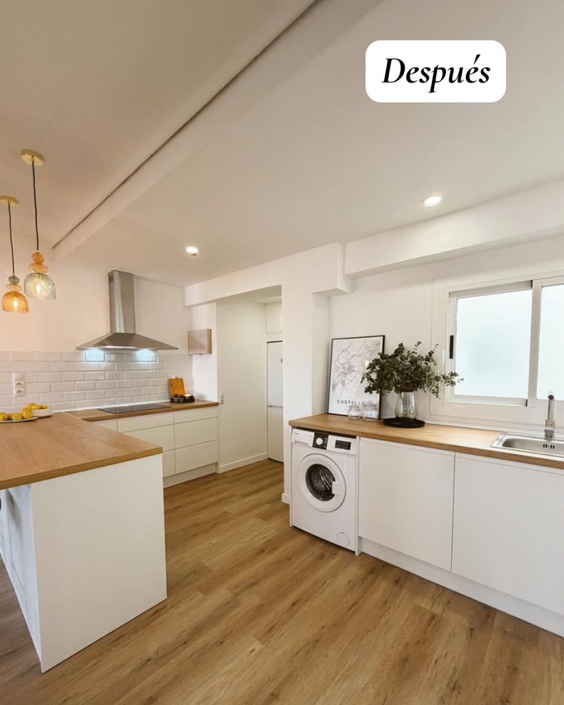Cocina abierta al salón con barra, suelo efecto madera y muebles blancos tras reforma integral en Castellón